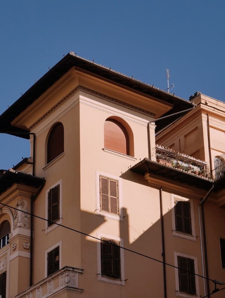 Peach Italian building with arched windows and terracotta shutters